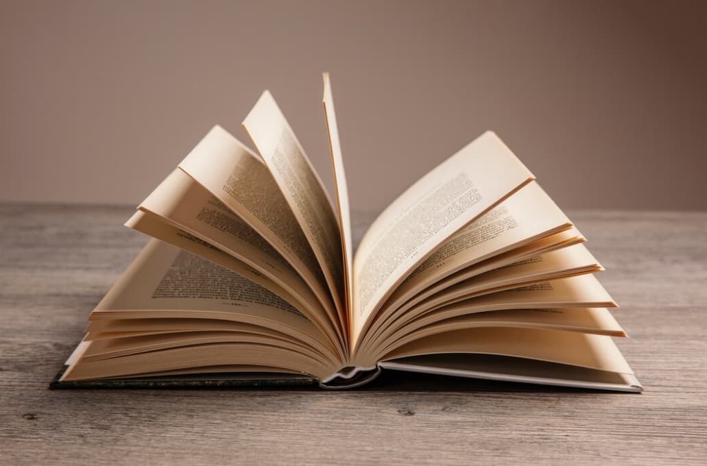 Open book on a wooden table casting a warm shadow