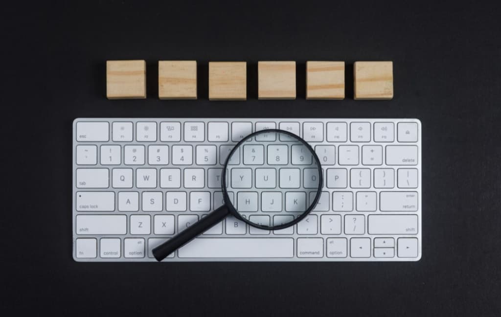 A magnifying glass focusing on the word "HACK" on a keyboard