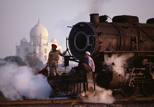 a beautiful photo of Indian men riding on the front of a steam locomotive
