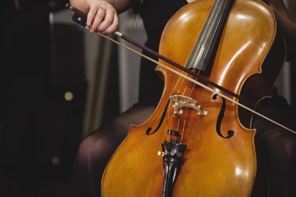 A cellist's hands drawing a bow across the strings of a cello during a performance