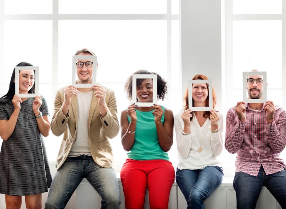 A group of people holding digital tablets over their faces against a bright window